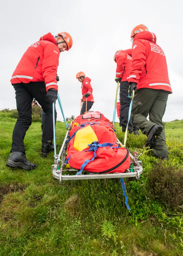 Team members carrying a stretcher with a casualty on it.
